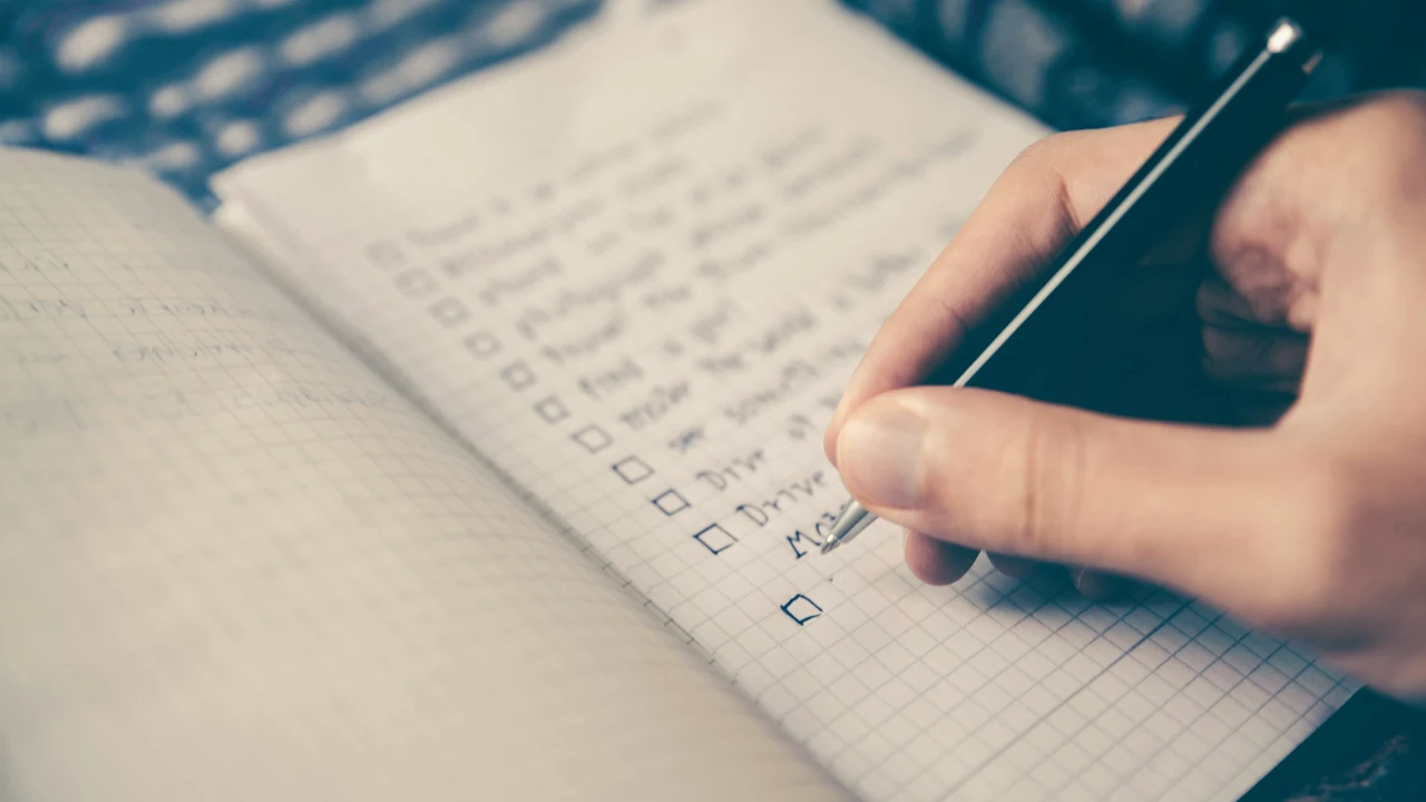 Hand writing a structured planning list in an open notebook.