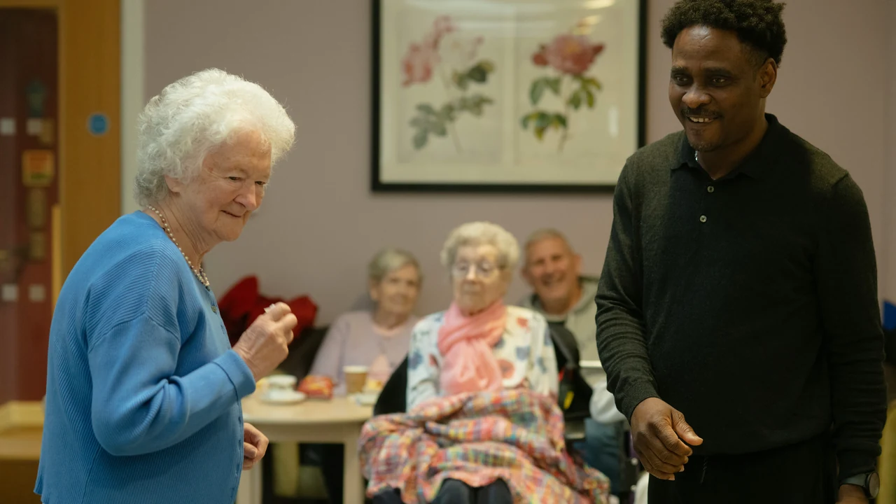 Authentic photograph of elderly people and caregiver in a common room.