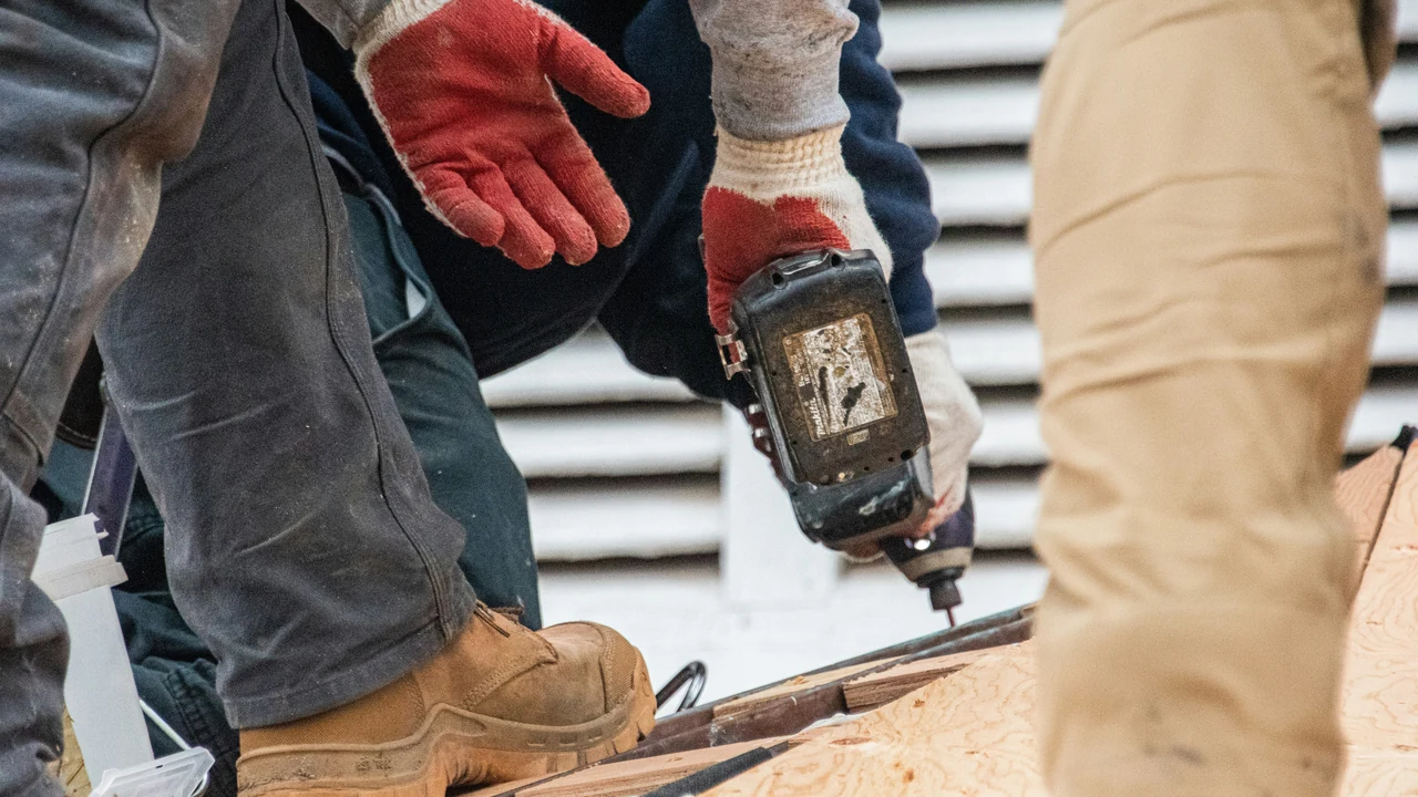 Authentic photograph of workers are using a drill on a roof.