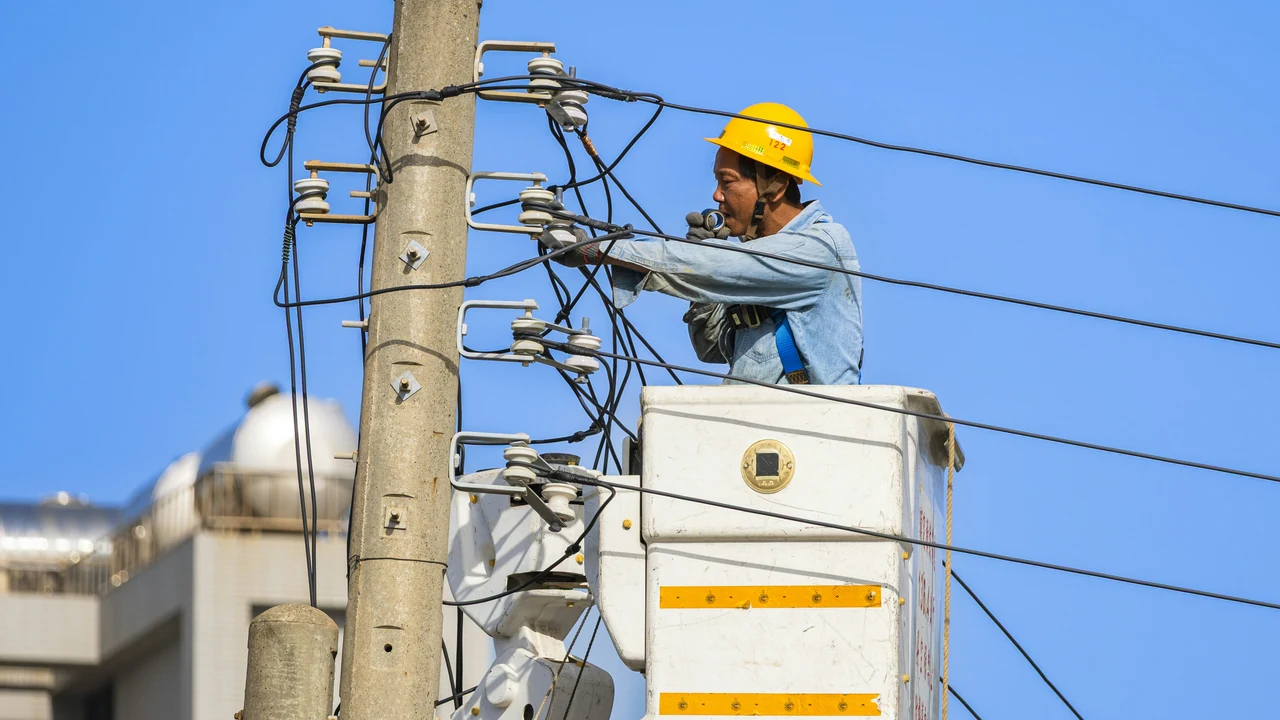 Authentic photograph of an electrician works on power lines from a lift.
