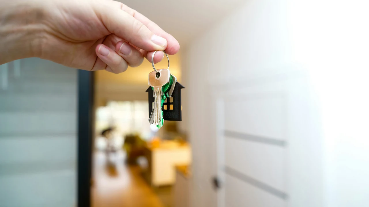 Hand holding house keys at a real property entrance.