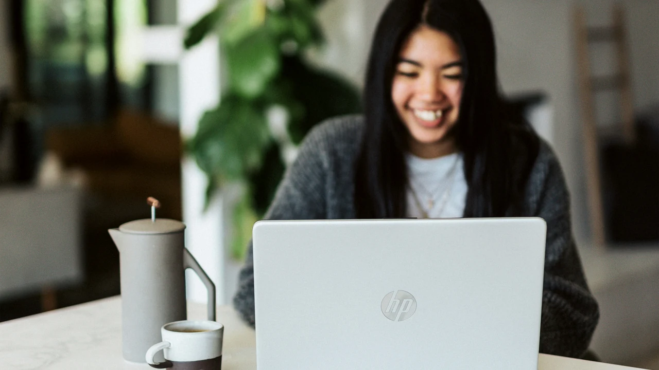 Authentic photograph of woman in gray sweater using laptop.