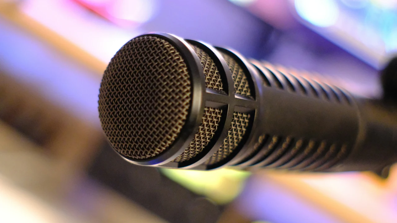 Authentic photograph of a black microphone against a blurred colorful background.
