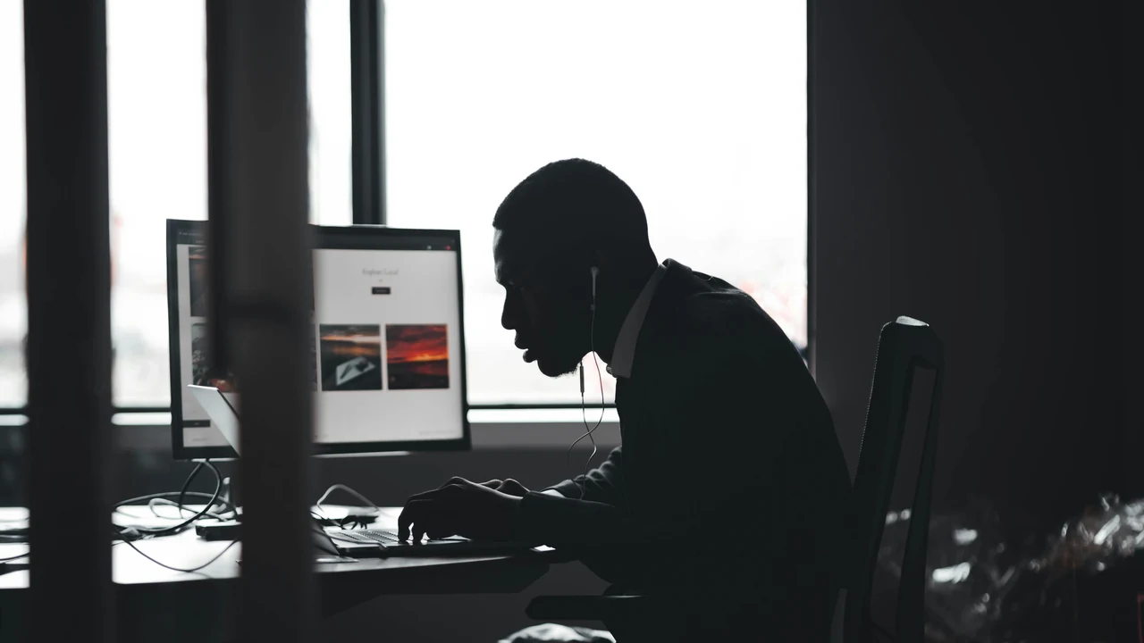 Authentic photograph of a man sitting at a desk using a computer.