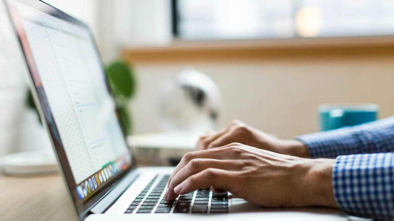 Authentic photograph of person typing on silver macbook.