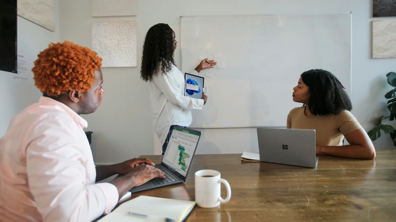 Authentic photograph of three people in an office working with their microsoft laptops.