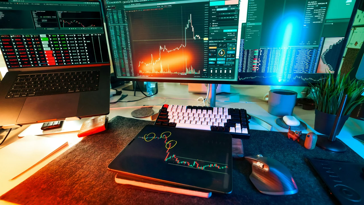Authentic photograph of a traders desk is lit up with charts.