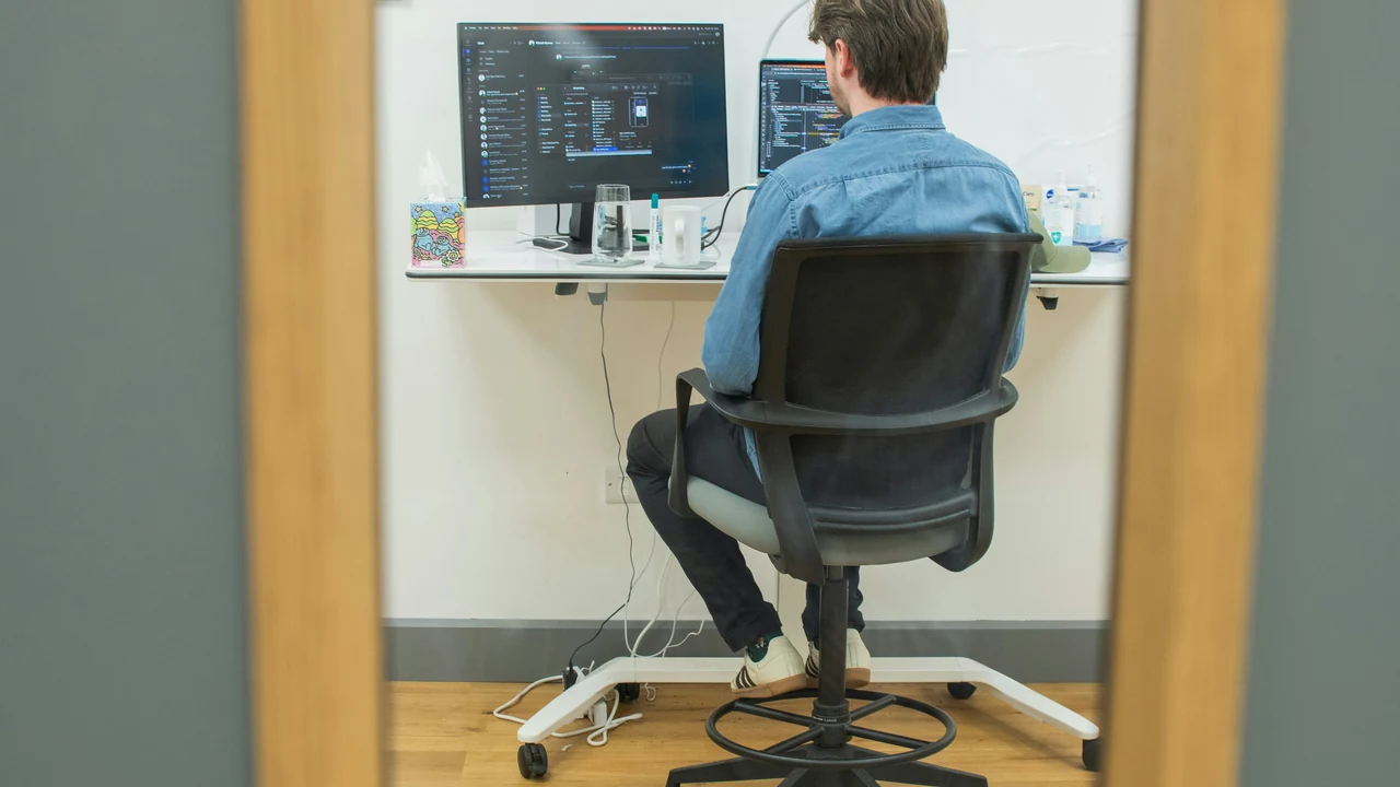 Authentic photograph of man working on computer in modern office.