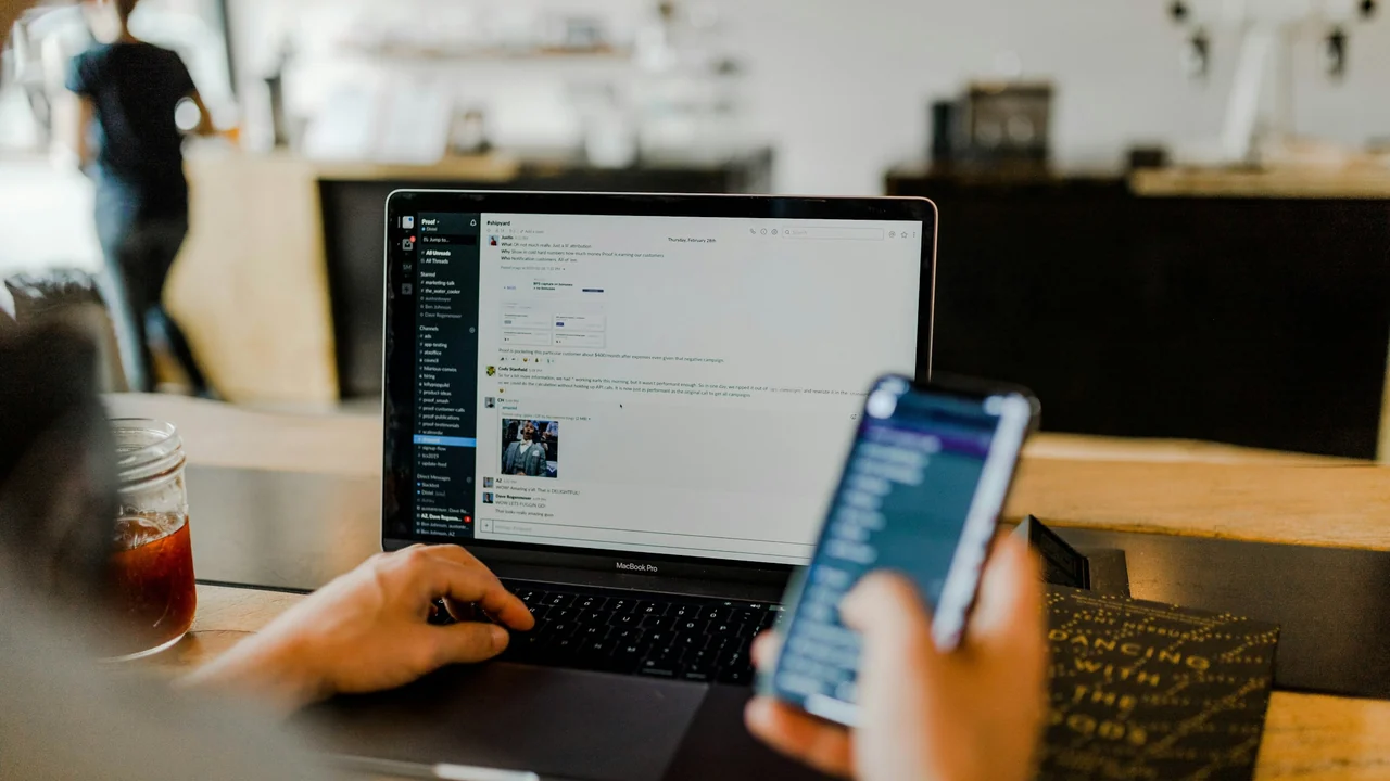 Person coordinating a business inquiry between a smartphone and laptop.