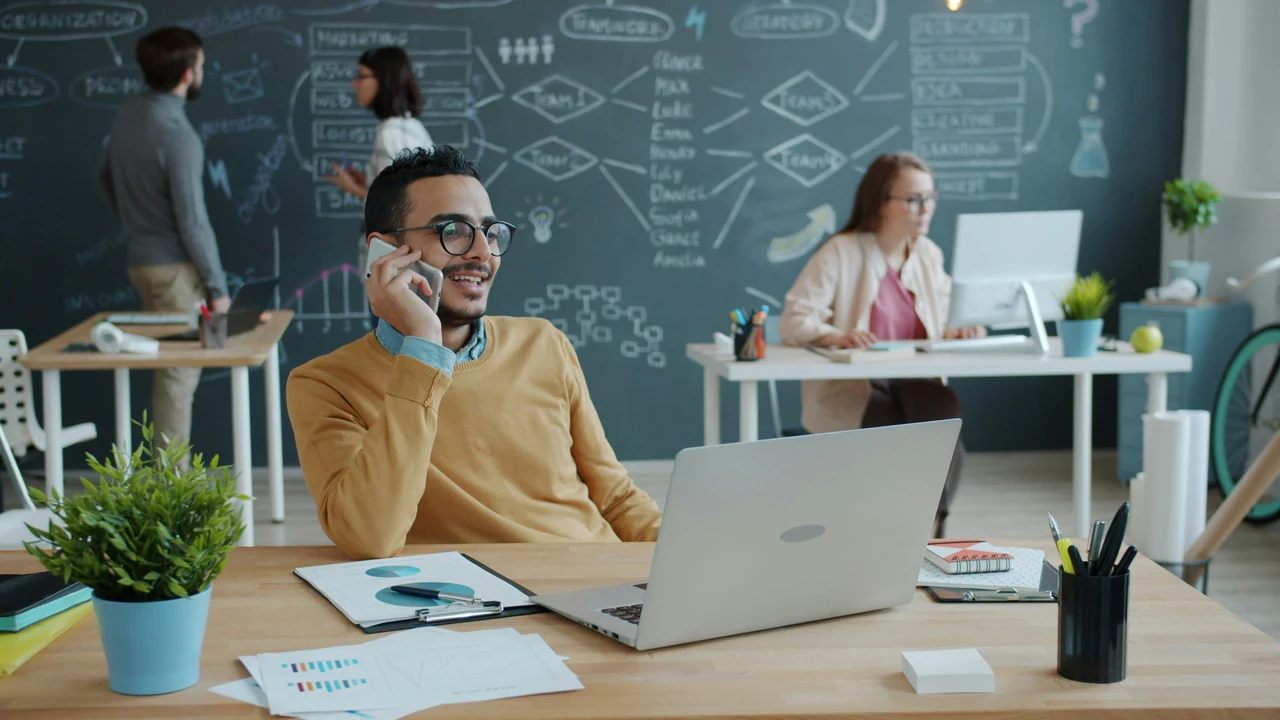 Man talking on phone in modern office with team.
