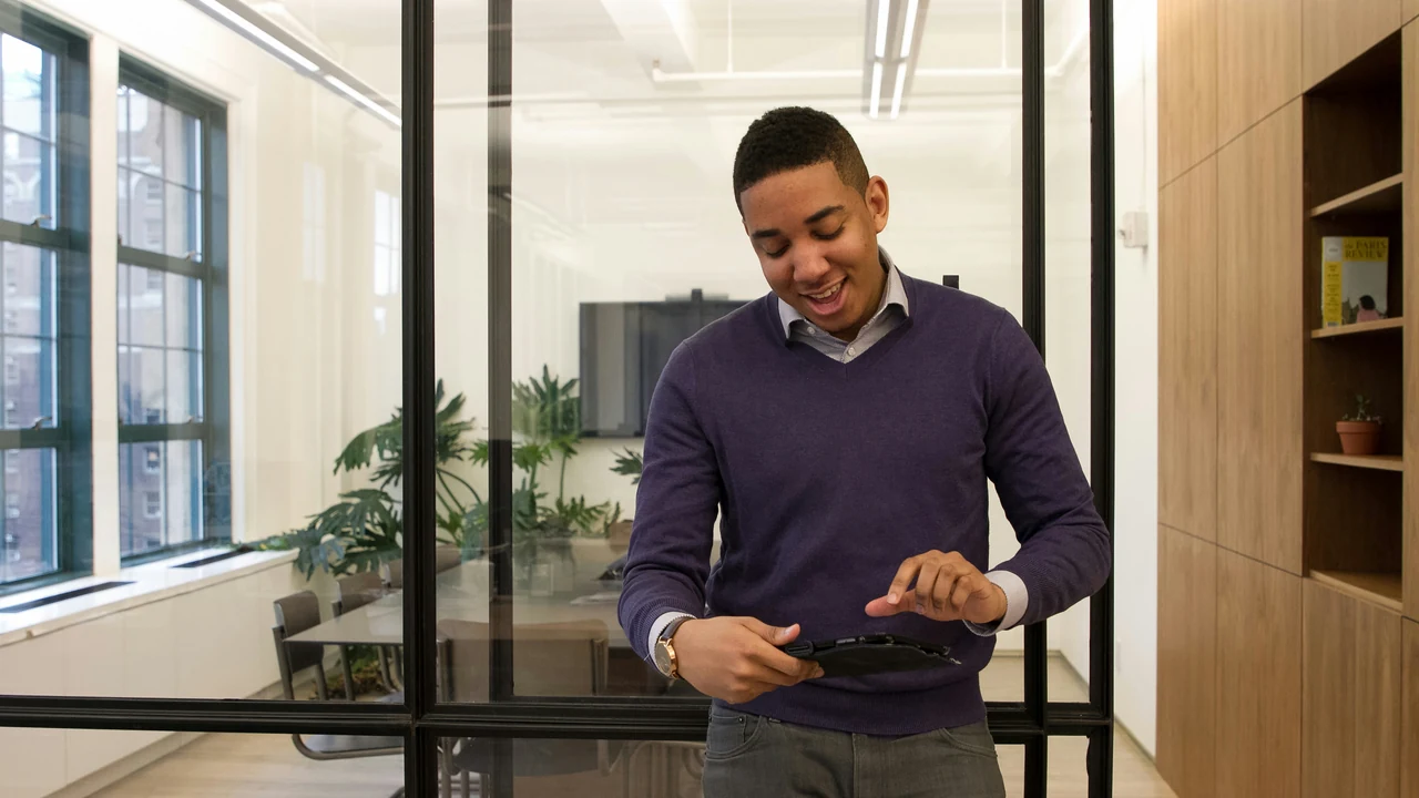 A man standing in an office looking at a cell phone.