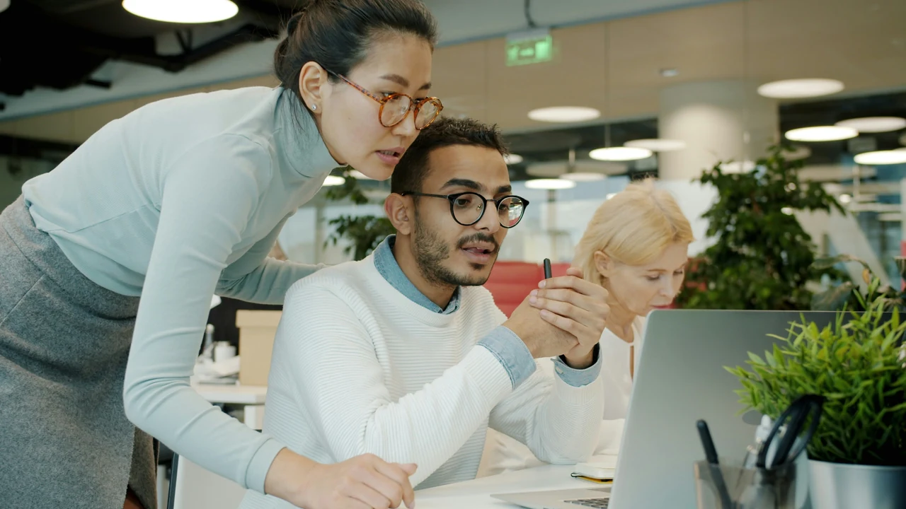 Two colleagues collaborating around a computer screen.
