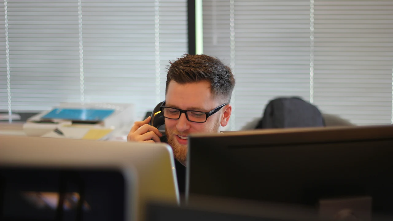Professional handling a business phone call at a desk.