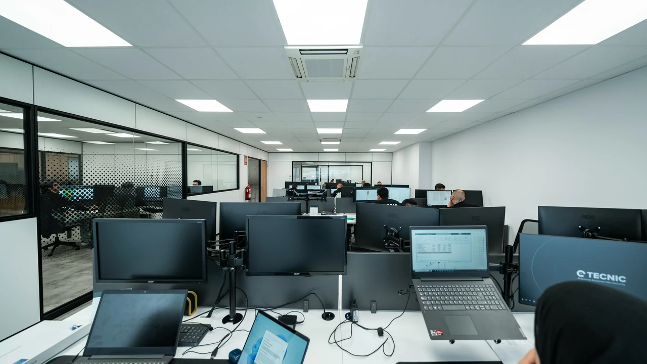 Technical team working across multiple coordinated office workstations.
