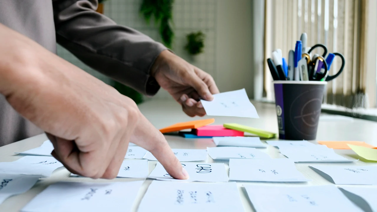 Hands arranging content cards during an information architecture exercise.