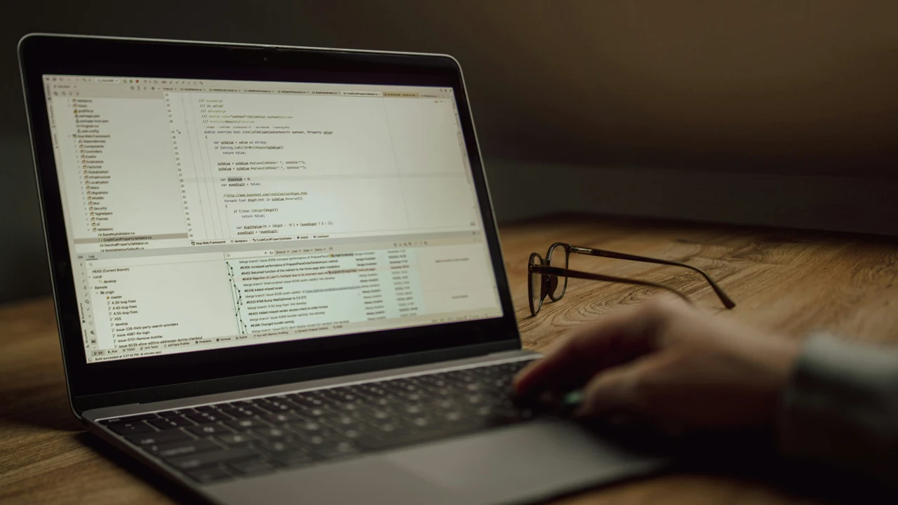 Developer typing on a laptop while reviewing website code.