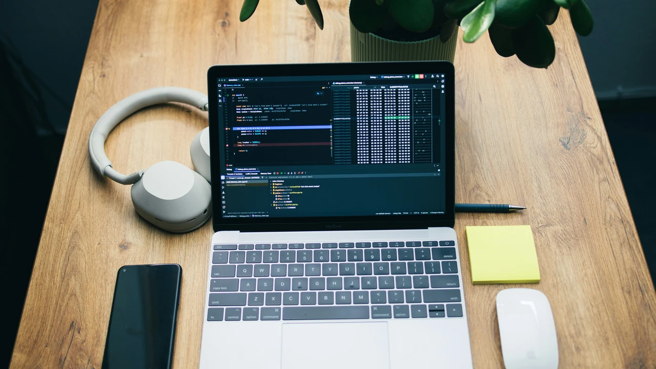 Developer workspace with laptop code and mobile device for speed testing.