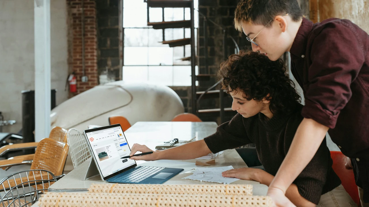 Designer and collaborator reviewing a laptop.