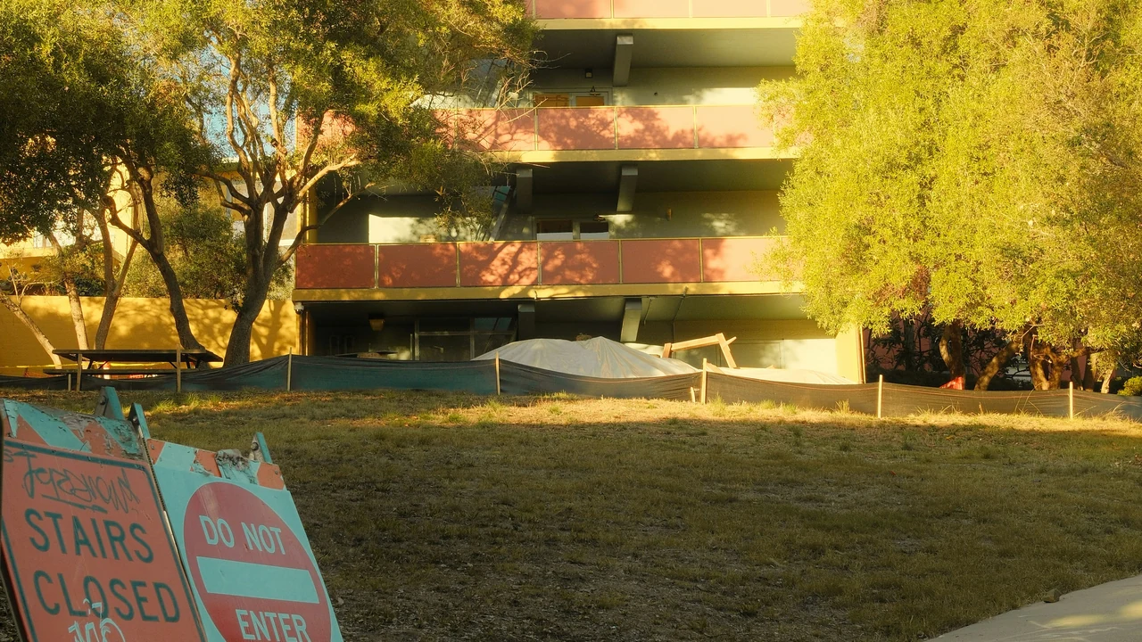Building with trees and caution signs on grass.