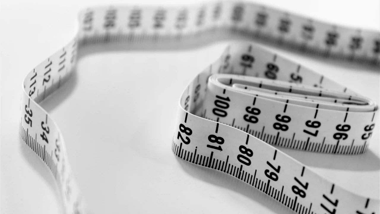 Close-up of a measuring tape extending across a wooden surface.